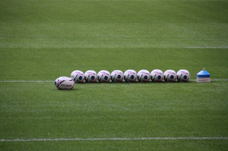 Piłki do piłki nożnej wraz ze znacznikami oraz piłką do rugby na murawie