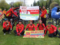 Rowerzyści trzymają baner z informacją o chorym Michałku podczas 12 rodzinnego rajdu po olkuskich szlakach rowerowych oraz nordic walking