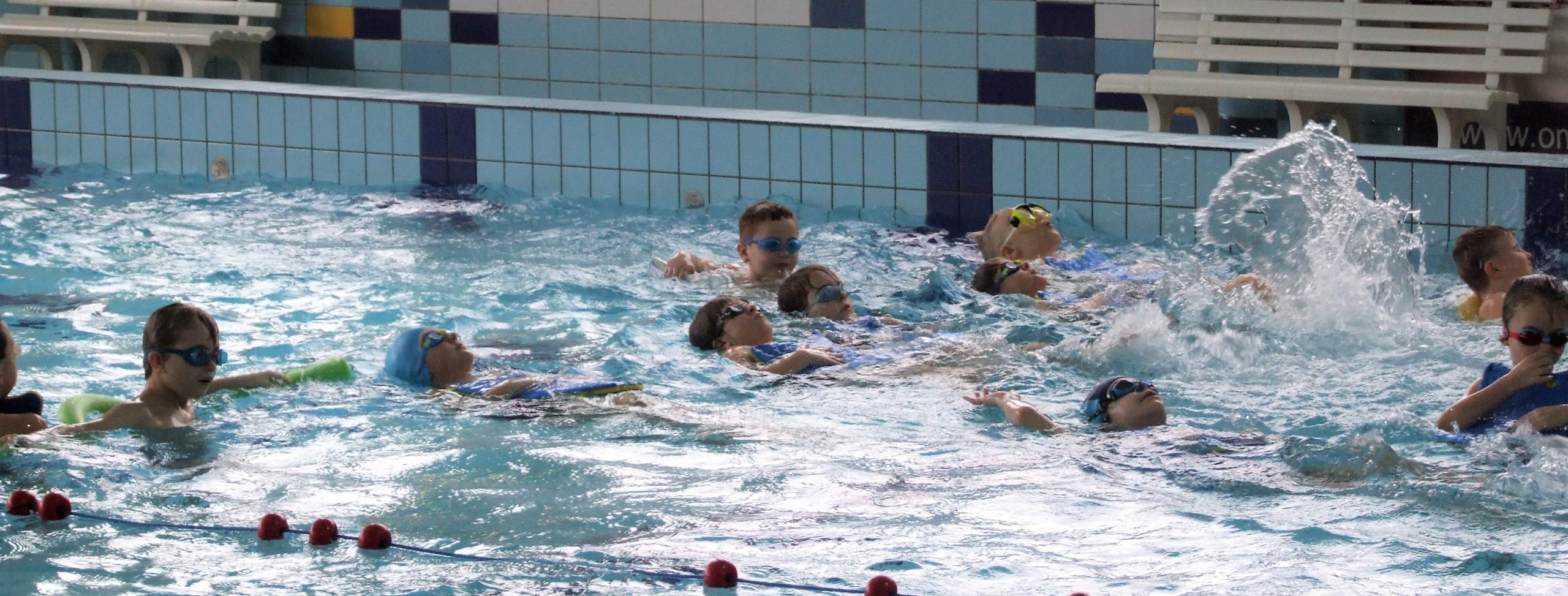 Dzieci pływają w basenie podczas zajęć Ferii z MOSiR'em