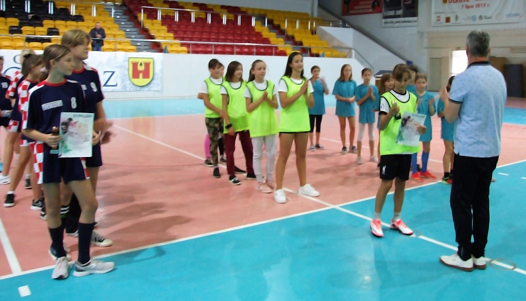 Zawodniczka odbiera puchar podczas dekoracji Igrzysk Dzieci w halowej piłki nożnej